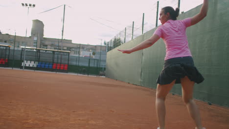 Seitenansicht-Einer-Jungen-Kaukasischen-Frau,-Die-Auf-Einem-Platz-Tennis-Spielt-Und-In-Zeitlupe-Einen-Ball-Zurückschlägt